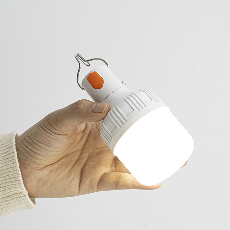 Lámpara LED LIHANGSTAR encendida sostenida en una mano, con cuerpo blanco, detalle naranja y gancho